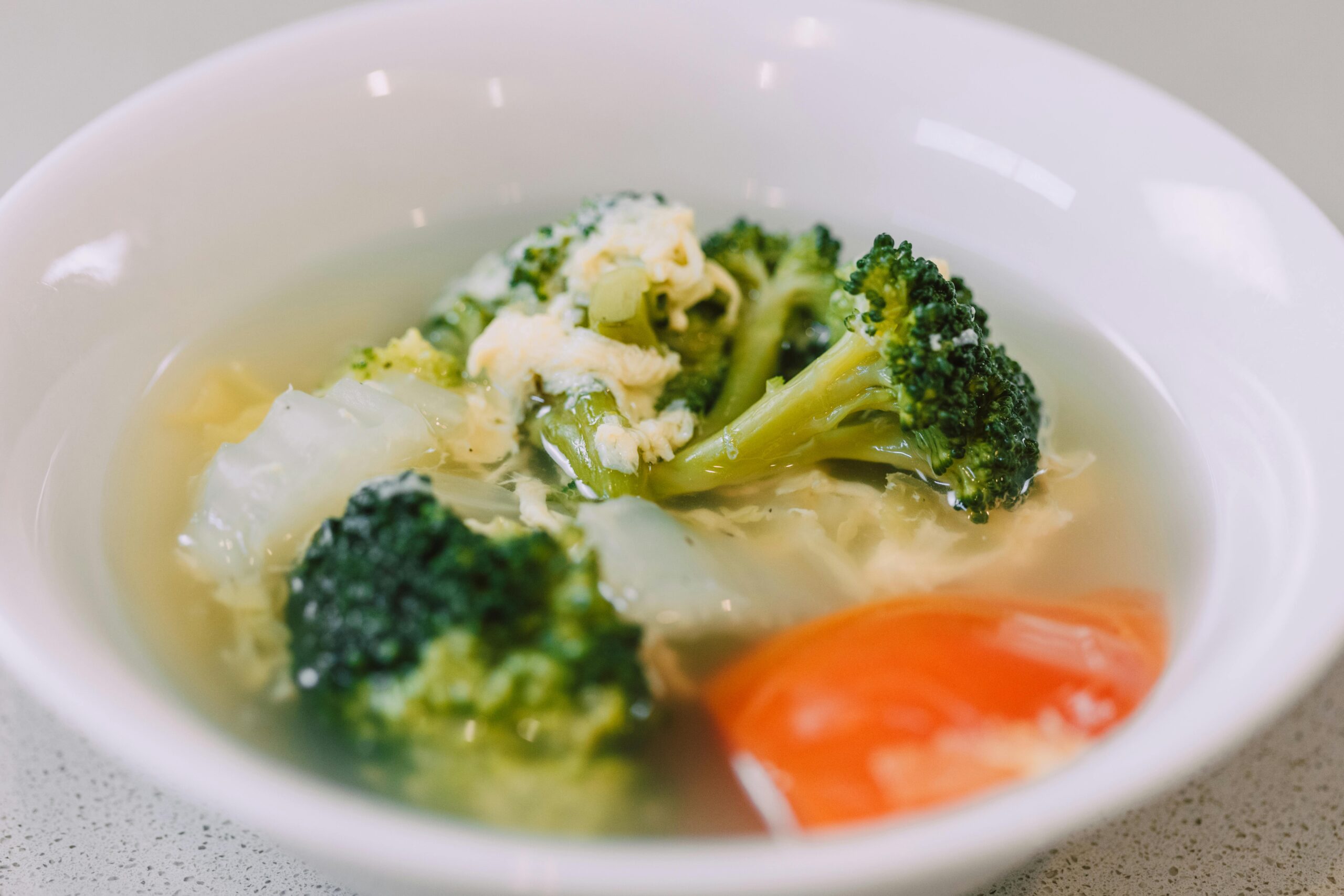 Appetizing broccoli soup with veggies in white bowl, perfect for health food concepts.