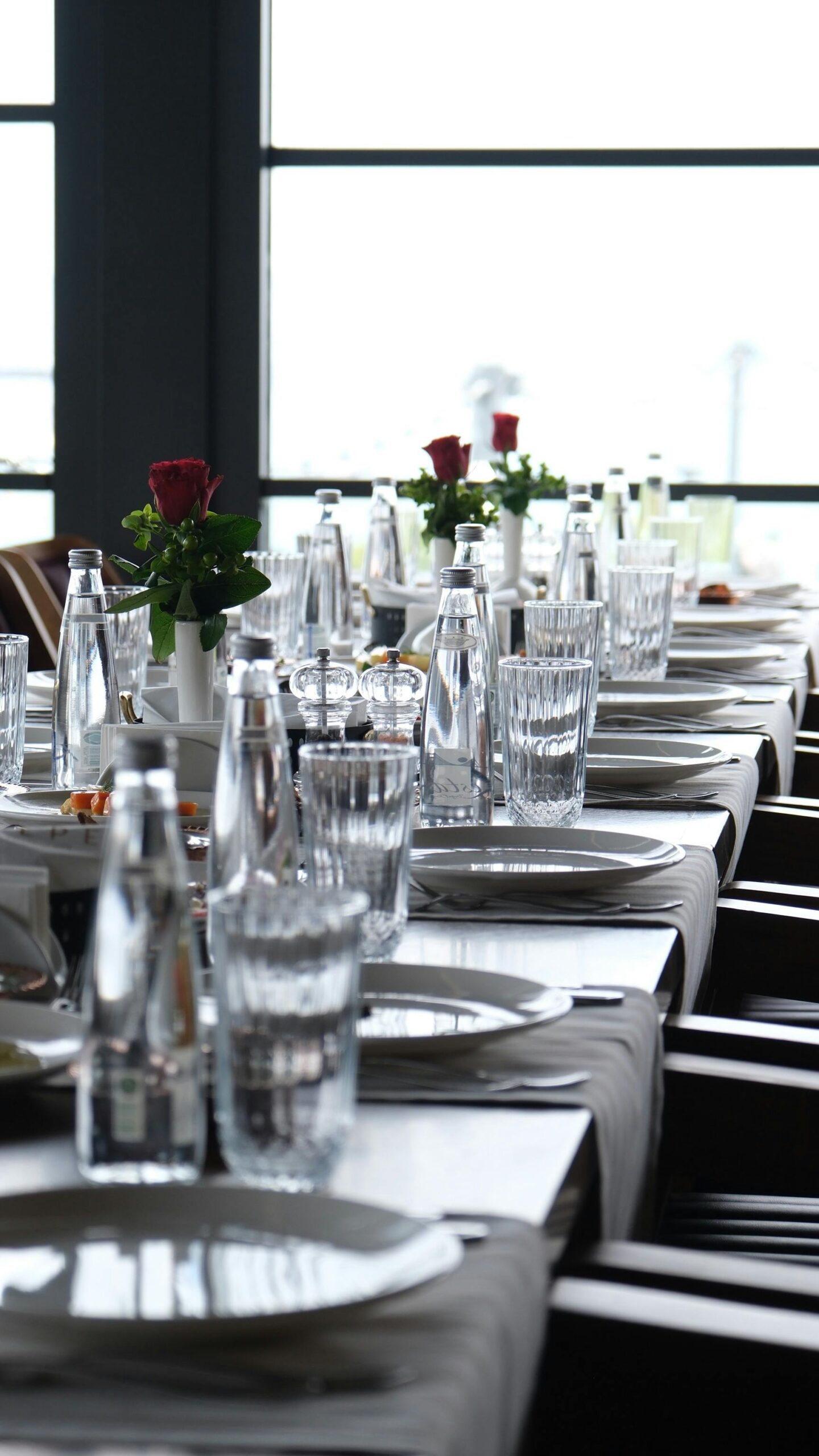 Chic table setup with glassware and red roses in a modern restaurant.